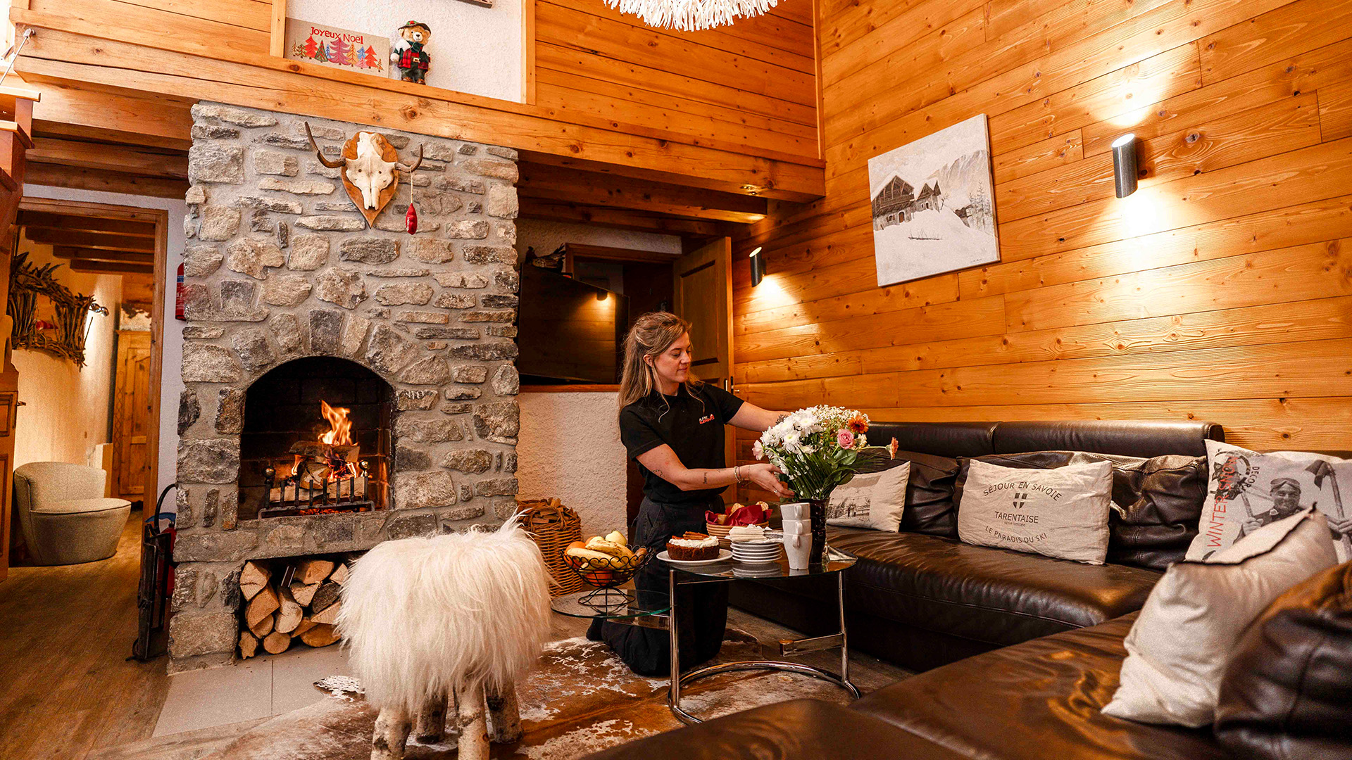 Alpine elements staff dressing a cosy chalet within its lounge area with a fire lit
