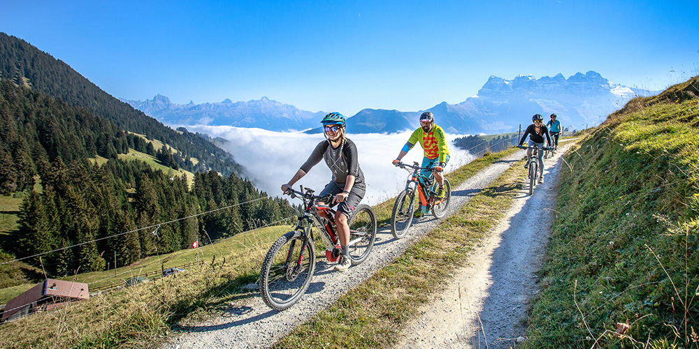 A group of riders on e-bikes on a track over Morzine valleys
